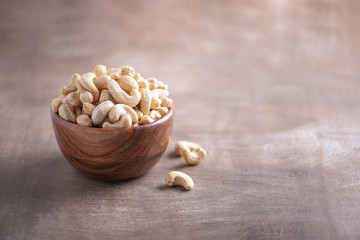 Cashew nuts in wooden bowl on wood textured background. Copy space. Superfood, vegan, vegetarian food concept. Macro of walnut texture, selective focus. Healthy snack