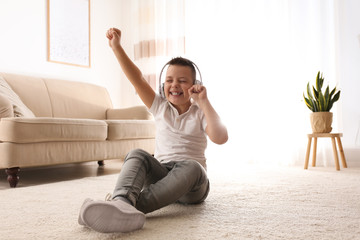 Wall Mural - Little boy listening to music on floor at home