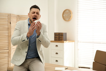 Wall Mural - Sick man sneezing in office. Influenza virus