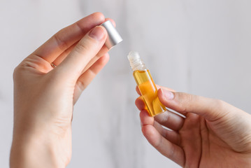 Oil aromatic perfumes made of natural essential oils on a bright white marble background in hand. Roller glass bottle. Aromatherapy, aromapsychology.