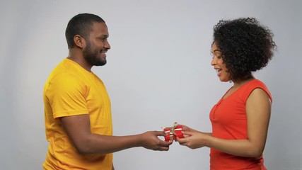 Wall Mural - holiday, greeting and people concept - happy african american couple with small red gift box over grey background