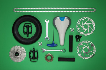 Wall Mural - Set of different bicycle tools and parts on green background, flat lay