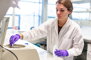 Female researcher loading samples in centrifuge in laboratory