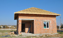 Building A Simple Brick House With Incomplete Hip, Bonnet Roof On The Stage Of Framing From Wooden Trusses, Roof Beams.
