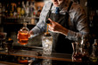 © fesenko - bartender using beaker pours drink into glass shaker