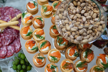 Wall Mural - Top view of banquet table with fish, nuts, cold meats. Variety of tasty delicious snacks. Selective focus. Corporate birthday party event or wedding celebration. Food concept