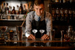 © fesenko - bartender holds two glasses with ice on bar counter.