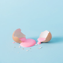 Eggshell With Pastel Pink Paint. Creative Copy Space On Blue Background. Minimal Easter Holiday Concept.