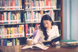 © BigBlues - Young beautiful asian student girl working a book, learning in college library in university