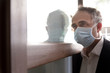 Uomo con mascherina chirurgica attraversa la porta di casa con aria preoccupata