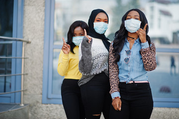 Group of three african american young volunteers wearing face mask outdoors. Coronavirus quarantine and global pandemic.