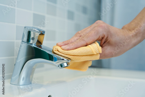 Fotomural man cleaning the faucet of a sink