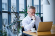© DSMT - Male freelancer is working in a cafe on a new business project. Sits at a large window at the table. Looks at a laptop screen with a cup of coffee
