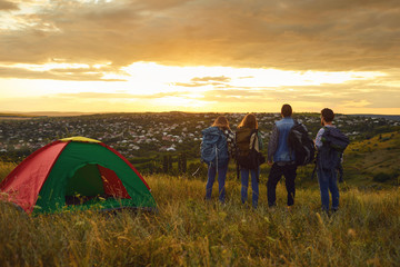 Wall Mural - Camping tent camp people tourists standing the sunset in nature.