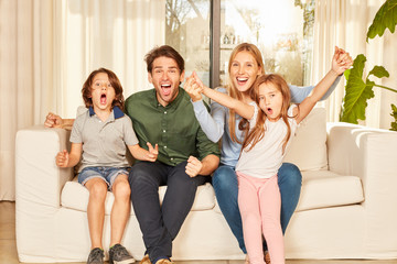 Wall Mural - Jubelnde Familie mit zwei Kindern auf dem Sofa