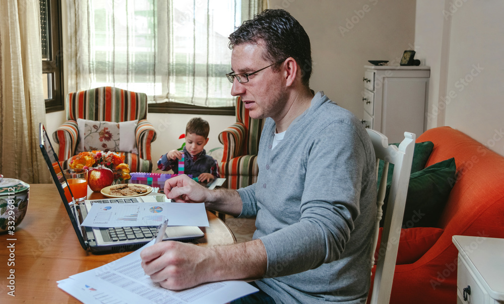 Father working at home while her son plays - obrazy, fototapety, plakaty 