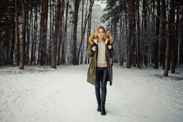 Woman in jacket on background of snowy trees for walk in winter forest