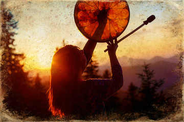 beautiful shamanic girl playing on shaman frame drum in the nature, old photo effect.