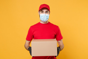 Delivery man employee in red cap blank t-shirt uniform face mask glove hold empty cardboard box isolated on yellow background studio Service quarantine pandemic coronavirus flu virus 2019-ncov concept