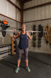 © rzcreative/Stocksy - A fit woman in her seventies smiles confidently with a weighted bench press bar on her shoulders.