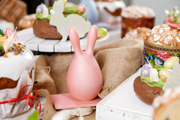 Wall Mural - Easter table orthodox sweet bread, kulich with chocolate eggs and rabbit. Variety pastries for holiday