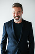 © Bonninstudio/Stocksy - Portrait of a happy mature man wearing a cool black suit.