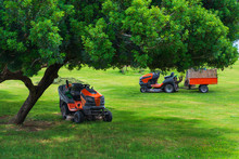 Lawn Mower Machines On Green Field. Summer Garden Ritual