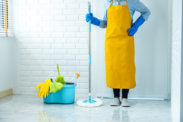 Housekeeping and cleaning concept, Happy young woman in blue rubber gloves wiping dust using mop while cleaning on floor at home