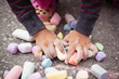 © absphotography/Stocksy - Closeup of the hands of a toddler child picking up her pieces of chalk after drawing on the asphalt driveway