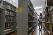© Milles Studio/Stocksy - Young woman picking books in public library