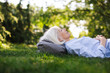 © Rob and Julia Campbell/Stocksy - Mature woman lying in the green grass looking up.