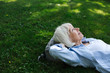 © Rob and Julia Campbell/Stocksy - Mature woman lying in the green grass looking up.