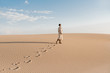 © Alina Hvostikova/Stocksy - Close up of traces on sandy dune from woman in beige coat.