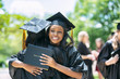 © Sean Locke Photography/Stocksy - Young women embracing each other after graduation ceremony on campus