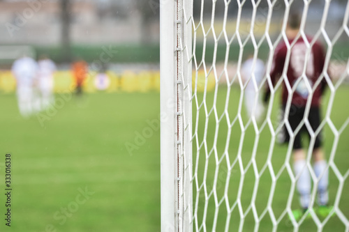 Photographie Detail of goal's post with net and football goalkeeper in the background