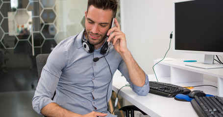 Wall Mural - Handsome young businessman talking on mobile phone in office