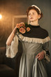 © Iuliia Versta/Stocksy - A portrait of a beautiful woman dressed in an old dress holding roses on her shoulder