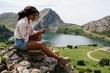 © Kike Arnaiz/Stocksy - Happy brown skinned woman typing on the phone the Europe Peaks in Asturias