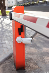 electric red barrier for autos in the parking lot with a surveillance camera for reading a car number