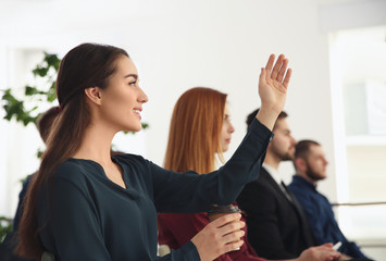 Wall Mural - Young woman raising hand to ask question at business training indoors