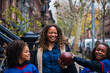 © Cavan Images - Happy girl holding American football while standing by sister and mother on footpath in city