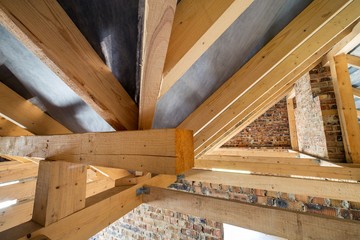 Wall Mural - Attic of a building under construction with wooden beams of a roof structure and brick walls.