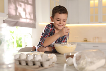 Wall Mural - Cute little boy cooking dough in kitchen at home