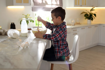 Wall Mural - Cute little boy cooking dough in kitchen at home