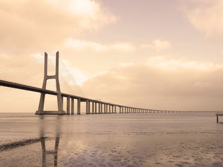 Bridge Vasco de Gama Lisbon crossing the river Tejo reflected in the water on a cloudy day.