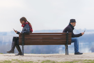 man and woman sitting apart on a bench