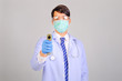 © I Believe I Can Fly - Medical doctor in white uniform doctor wears medical gloves, medical masks and and wearing protective glasses holding infrared forhead thermometer on gray background, corona virus concept