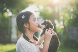 Fototapeta Koty - Beautiful asian girl playing with siberian husky puppy in the park