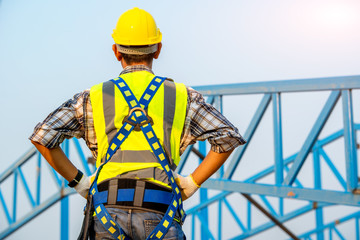 Portrait of construction worker wearing a yellow helmet looks instruments project standing at building construction site.