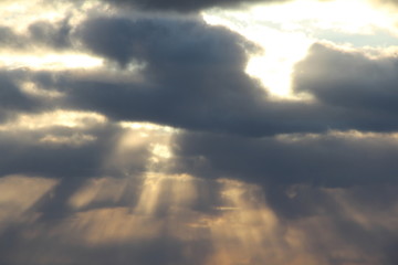 Wall Mural - the sun at sunset or dawn behind the clouds, shines through. the sun's rays in the sky